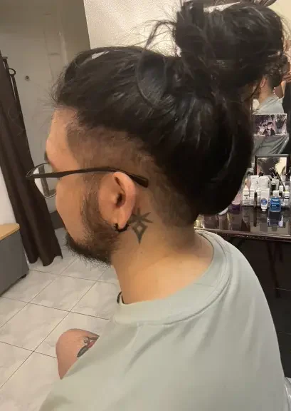 Men's long hair with shaved sides styled into a top donut bun
