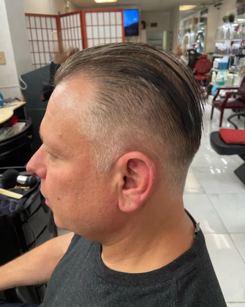 Two-block haircut showing shaved sides and a full, textured length on top