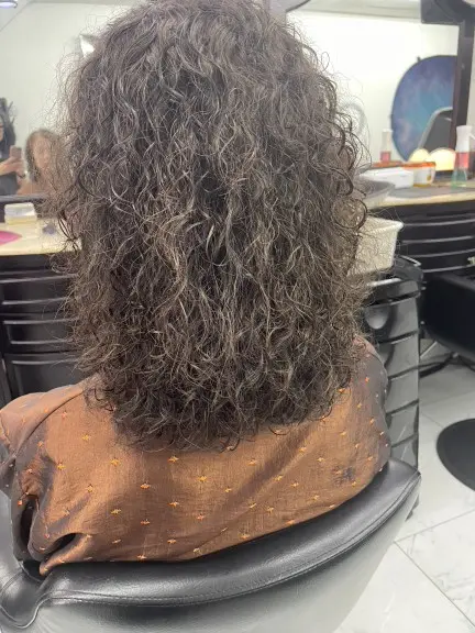 Back view of a Korean curly perm on a layered medium-length haircut