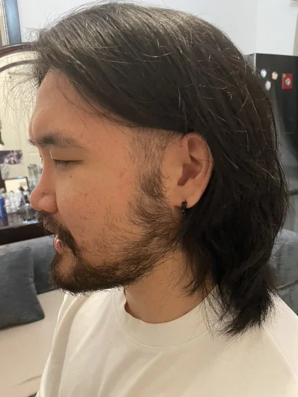 Textured wolf cut featuring heavily layered, shaggy top sections paired with cleanly shaved sides side view