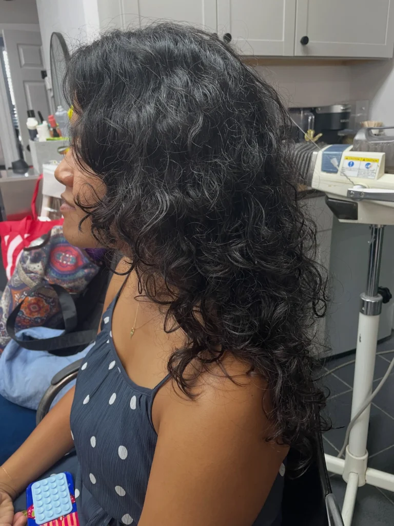 Side view of a Korean wolf cut on long curly hair with layered, textured length and face-framing curls
