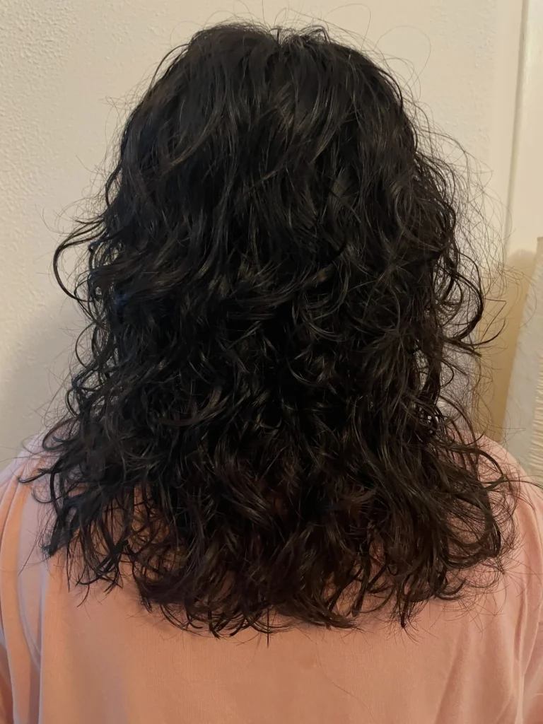 Vintage-style hippie perm with dense, textured curls and soft retro volume back view