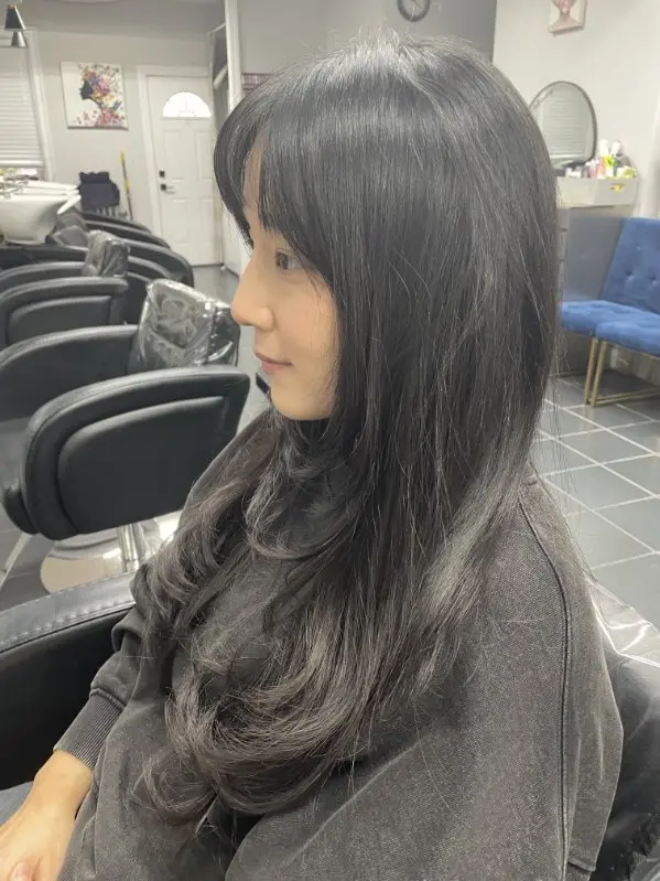 Long layered hairstyle seen from the left side, showing face-framing layers and feathered ends
