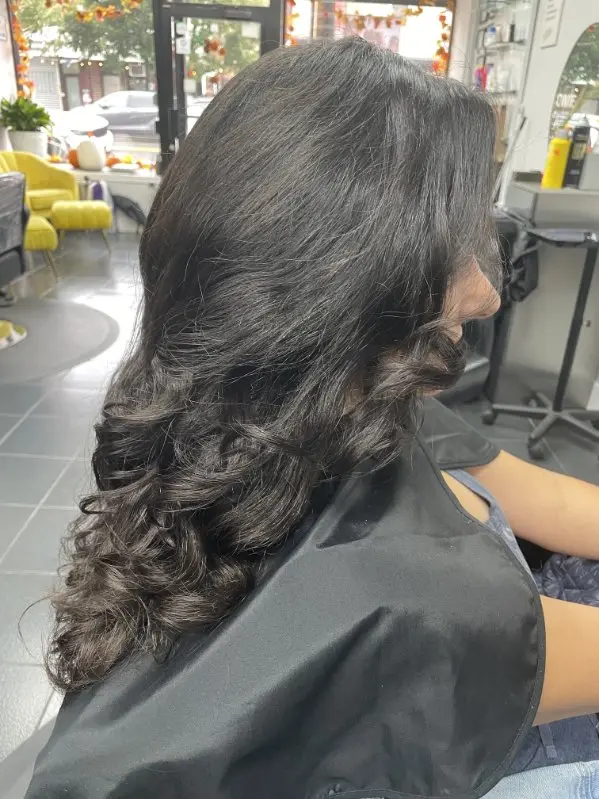 Side view of a long wavy blowout with soft voluminous curls and layered movement