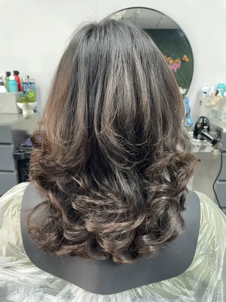 Women's medium layered haircut with soft curls, showing blended layers on dark brown hair